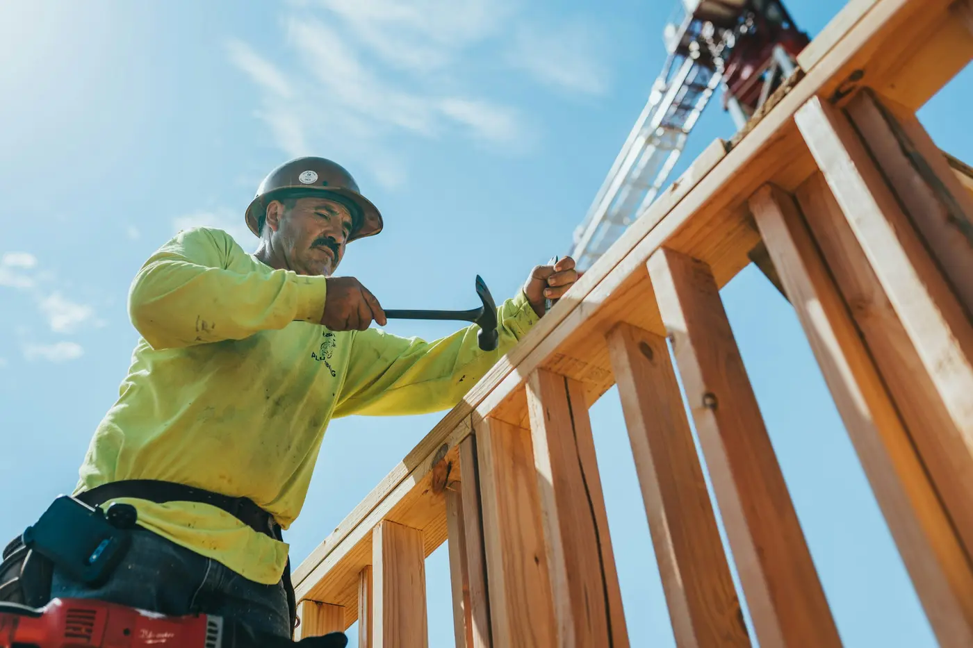 A construction worker in a hard hat hammering a wood frame