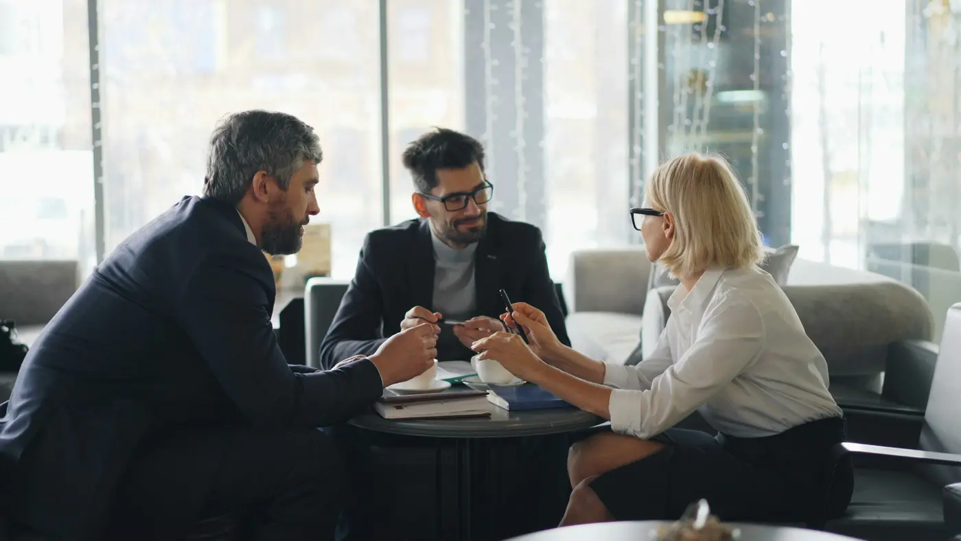 Three people in a meeting going over documents