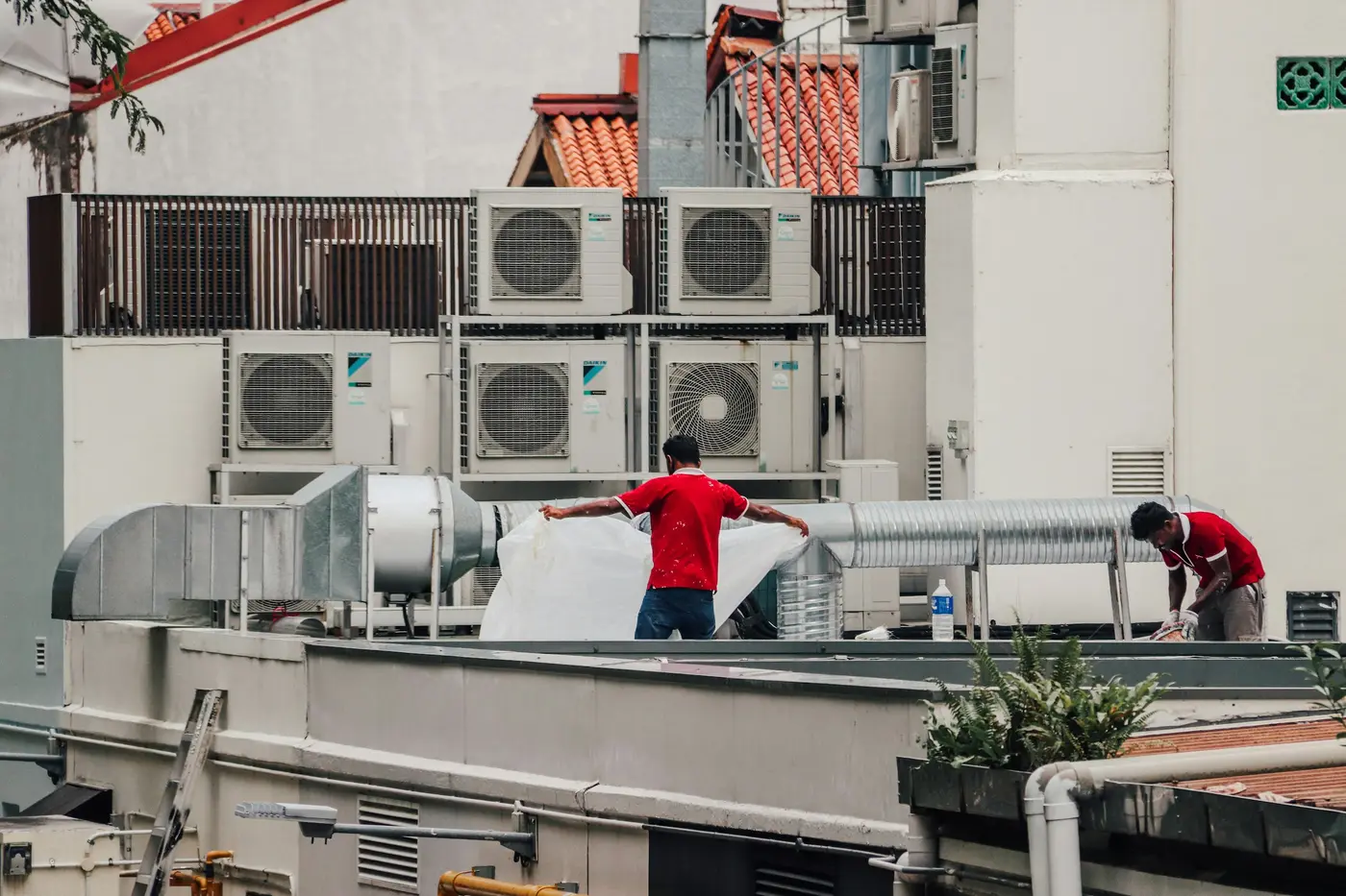 Workers on a rooftop among rows of air conditioning units